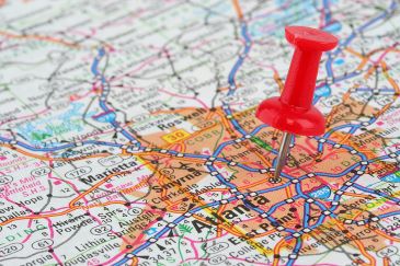 A red pushpin is stuck into a paper map, right in the center of Atlanta, GA.