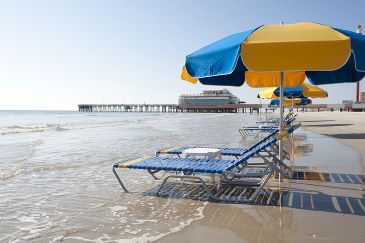 Lounge chairs and umbrellas are on the beach at Daytona Beach, FL