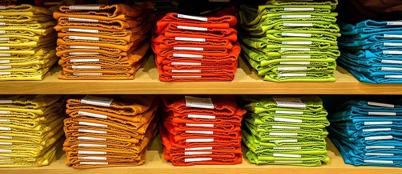 Neat piles of folded and stacked clothing on wood shelves