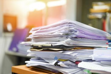 A stack of documents is sitting on a desk surface.